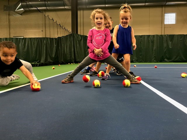 Children playing on tennis courts with tennis balls