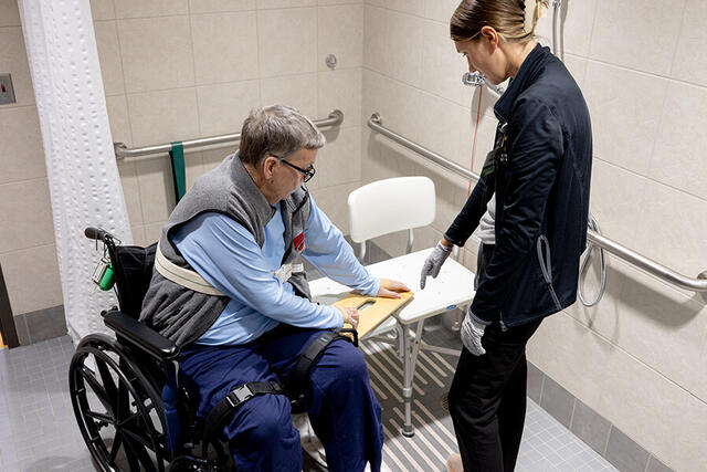 Mary Free Bed Carousel - Man in Wheelchair in Shower getting Physical Therapy Mary Free Bed Carousel - Man in Wheelchair in Shower getting Physical Therapy