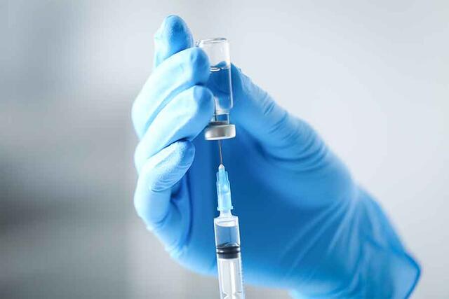 A syringe and vaccine vial | 900x600px
