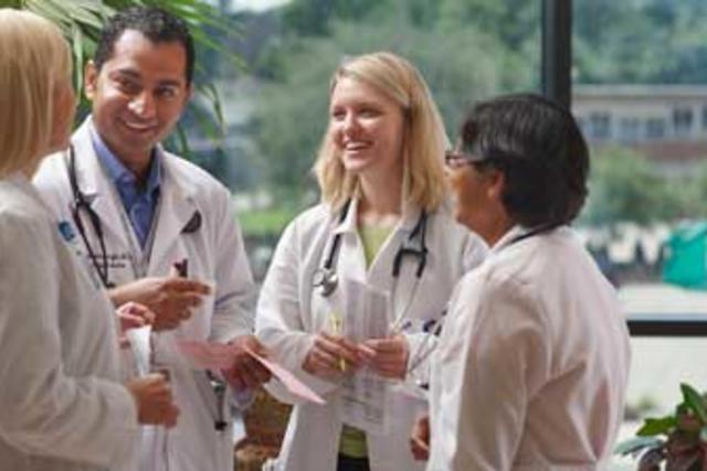 Group of male and female doctors standing together, mingling and smiling