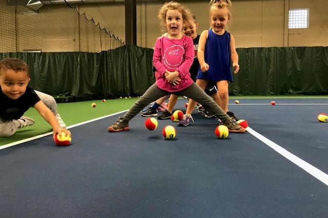 Children playing on tennis courts with tennis balls